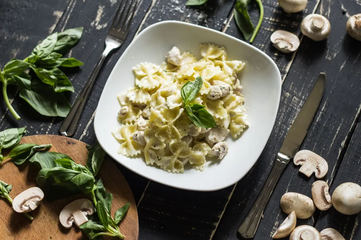 Creamy mushroom farfalle with basil on a wooden table